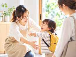 日本人の保育者と子どもが明るい室内で挨拶する